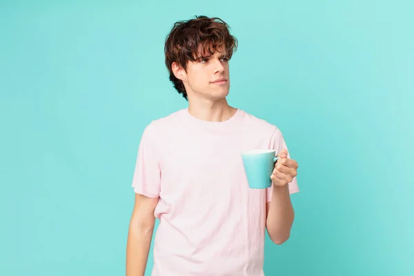 young man with a coffee mug feeling sad, upset or angry and looking to the side