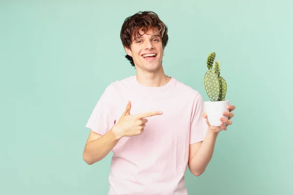 Jovem Com Cacto Sorrindo Alegremente Sentindo Feliz Apontando Para Lado — Fotografia de Stock