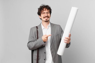 Genç mimar neşeyle gülümsüyor, mutlu hissediyor ve bir tarafı işaret ediyor.