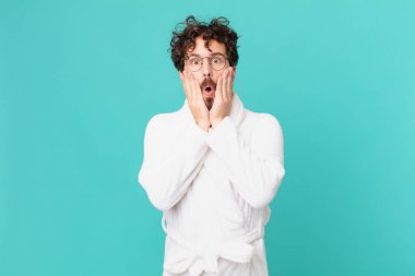 Bornoz giyen genç adam şok olmuş ve korkmuş hissediyor.