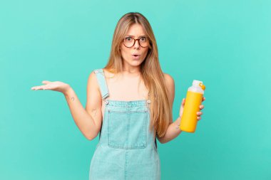 Genç bir kadın pürüzsüz görünümlü şaşırmış ve şok olmuş, çenesi düşmüş bir nesne tutuyor.