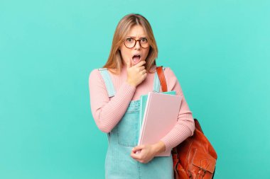 Ağzı ve gözleri açık, elleri çenesinde genç bir bayan öğrenci.