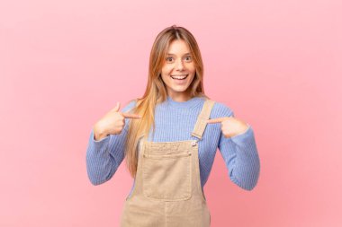 Genç bir kadın mutlu hissediyor ve heyecanla kendini işaret ediyor.