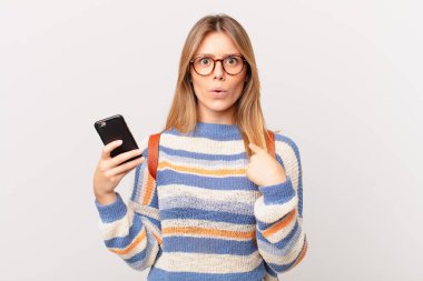 Şok olmuş ve ağzı açık, kendini işaret eden bir hücreye benzeyen genç bir kız.