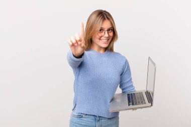 Dizüstü bilgisayarı olan genç bir kadın gururla gülümsüyor ve kendinden emin bir numara oluyor.