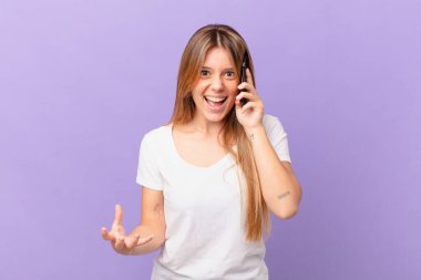 Cep telefonlu genç bir kadın sinirli, sinirli ve sinirli görünüyor.