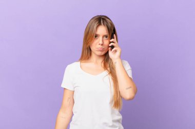 Cep telefonlu genç bir kadın üzgün ve sızlanıyor mutsuz bir bakışla ve ağlamayla