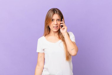Cep telefonlu genç bir kadın kafası karışık ve şaşkın.