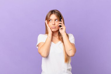 Cep telefonlu genç bir kadın bıkkın, bıkkın ve uykulu.