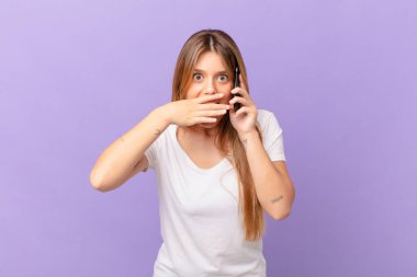 Cep telefonuyla ağzını kapatan genç bir kadın.