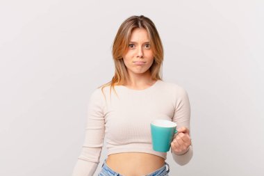 Elinde kahve fincanı olan genç bir kadın üzgün ve sızlanıyor mutsuz bir bakışla ve ağlıyor.