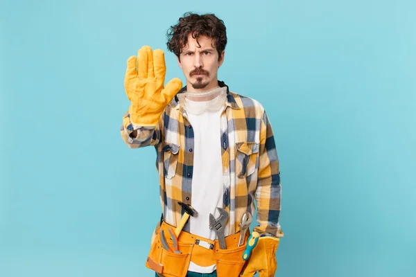 Young Handyman Housekeeper Looking Serious Showing Open Palm Making Stop — Φωτογραφία Αρχείου