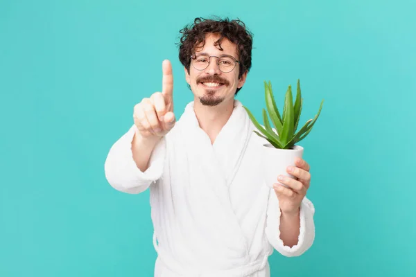 Joven Vestido Con Albornoz Sonriente Simpático Mostrando Número Uno —  Fotos de Stock