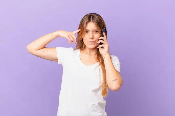 Ung Kvinna Med Mobiltelefon Känsla Förvirrad Och Förbryllad Visar Att — Stockfoto