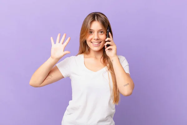 Jovem Mulher Com Telefone Celular Sorrindo Olhando Amigável Mostrando Número — Fotografia de Stock