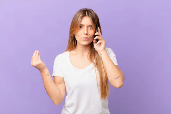 Νεαρή Γυναίκα Ένα Κινητό Τηλέφωνο Κάνει Capice Χειρονομία Χρήματα Σας — Φωτογραφία Αρχείου