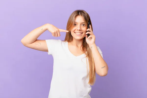 Ung Kvinna Med Mobiltelefon Ler Tryggt Pekar Egen Bred Leende — Stockfoto