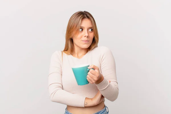 Jonge Vrouw Met Een Koffiemok Halen Zich Verward Onzeker Voelen — Stockfoto