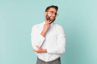 Genç yakışıklı adam mutlu bir şekilde gülümsüyor ve hayal kuruyor.