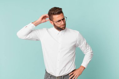 Kafası karışmış, kafası karışmış, kaşınan genç yakışıklı bir adam.