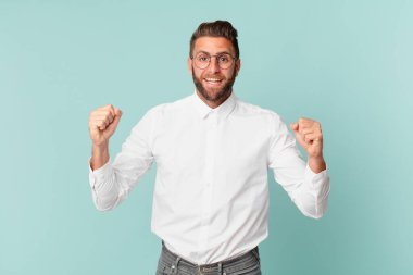 Genç yakışıklı adam şokta, gülüyor ve başarıyı kutluyor.