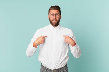 Genç yakışıklı adam mutlu hissediyor ve heyecanla kendini işaret ediyor.