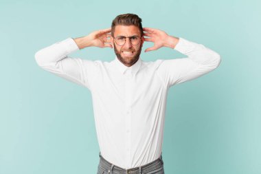 Genç ve yakışıklı adam stresli, endişeli ya da korkmuş, elleri başının üstünde.
