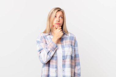 Genç sarışın kadın düşünüyor, kuşkulu ve şaşkın hissediyor.