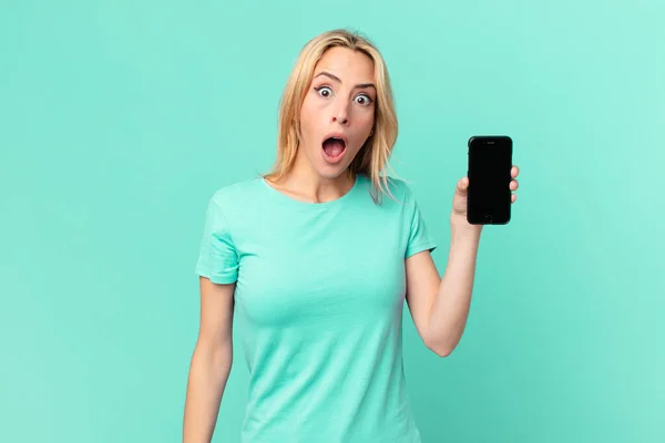 Mujer Rubia Joven Mirando Muy Sorprendido Sorprendido Sosteniendo Teléfono Inteligente —  Fotos de Stock