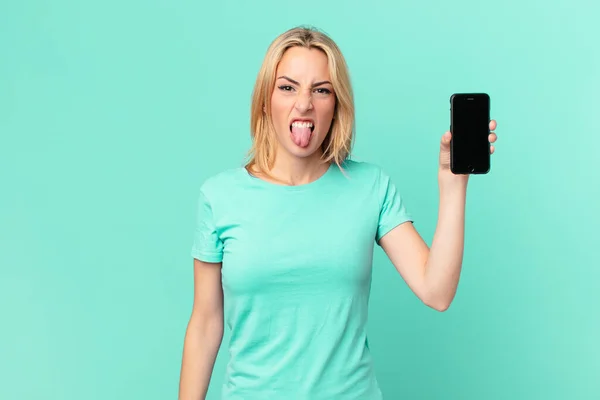 Młoda Blondynka Czuje Obrzydzenie Irytację Język Się Trzymając Smartfon — Zdjęcie stockowe