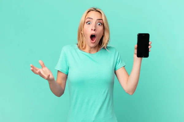 Joven Rubia Sintiéndose Extremadamente Sorprendida Sorprendida Sosteniendo Teléfono Inteligente —  Fotos de Stock
