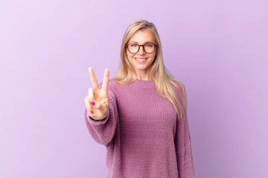 Genç sarışın kadın gülümsüyor ve arkadaş canlısı görünüyor.