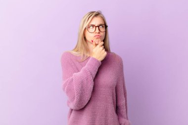 Genç sarışın kadın düşünüyor, kuşkulu ve şaşkın hissediyor.