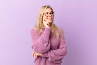 Genç sarışın kadın mutlu bir şekilde gülümsüyor ve hayal kuruyor.