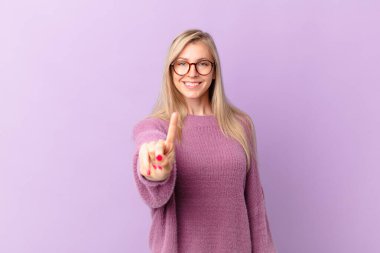 Genç sarışın kadın gülümsüyor ve arkadaş canlısı görünüyor.