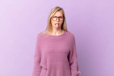 Genç sarışın kadın iğreniyor, sinirleniyor ve dilini çıkarıyor.