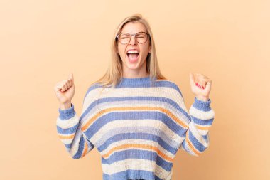 Genç sarışın kadın sinirli bir ifadeyle agresif bir şekilde bağırıyor.