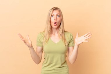 Genç sarışın kadın şok olmuş ve şaşırmış hissediyor.