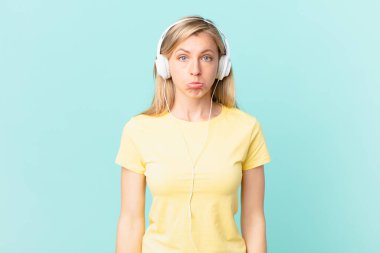 young blonde woman feeling sad and whiney with an unhappy look and crying and listening music.