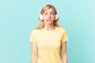 young blonde woman looking puzzled and confused and listening music.