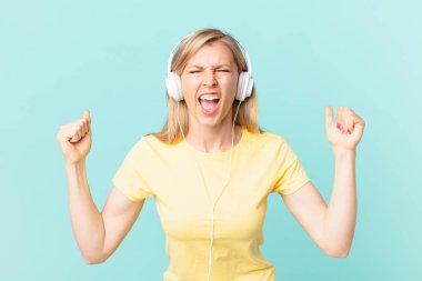 young blonde woman shouting aggressively with an angry expression and listening music.