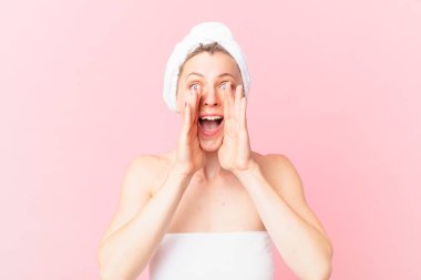 Genç sarışın kadın kendini mutlu hissediyor, elleri ağzının yanında ve duştan sonra kocaman bağırıyor.