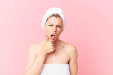 Genç sarışın kadın ağzı ve gözleri sonuna kadar açık ve elleri çenesinde ve duştan sonra