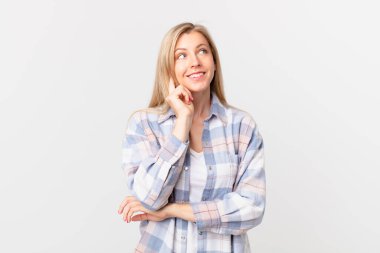 Genç sarışın kadın mutlu bir şekilde gülümsüyor ve hayal kuruyor.