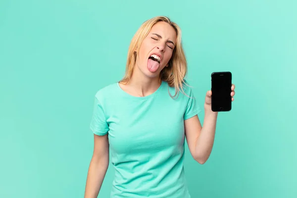 Młoda Blondynka Wesołym Buntowniczym Nastawieniem Żarty Wystające Język Trzymając Smartfon — Zdjęcie stockowe