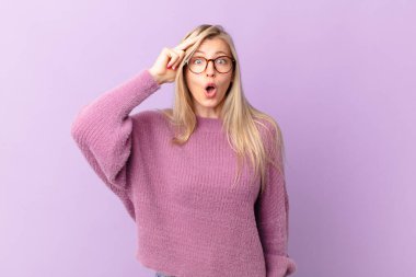 Genç sarışın kadın mutlu, şaşkın ve şaşkın görünüyor.