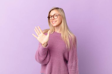 Genç sarışın kadın gülümsüyor ve arkadaş canlısı görünüyor.