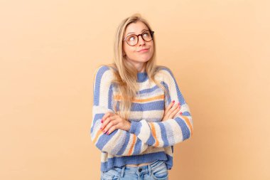 Genç sarışın kadın omuz silkiyor, kafası karışık ve kararsız.