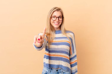 Genç sarışın kadın gülümsüyor ve arkadaş canlısı görünüyor.