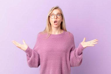 Genç sarışın kadın şok olmuş ve şaşırmış hissediyor.